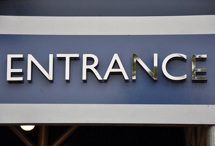 A blue and grey sign with raised metallic letters, reading ENTRANCE.
