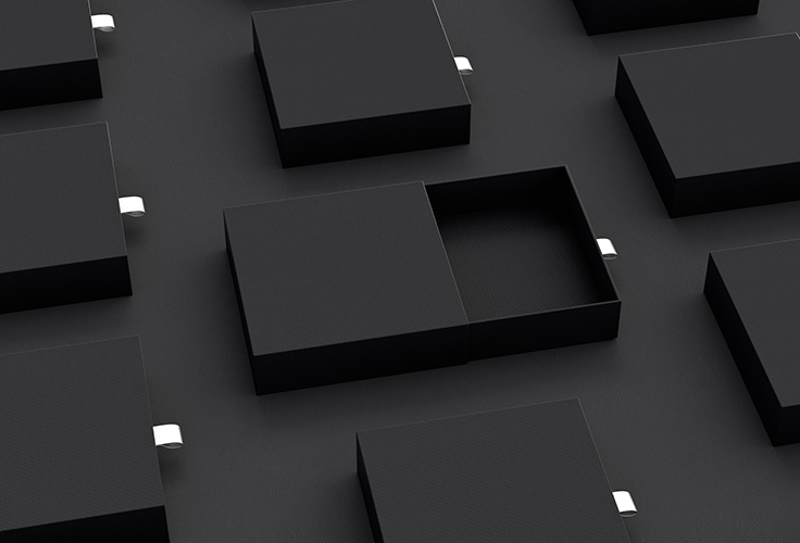 A top-down view of 9 black boxes with white pull-tabs, arrayed in a grid on a black surface. The drawer of the center box is open.